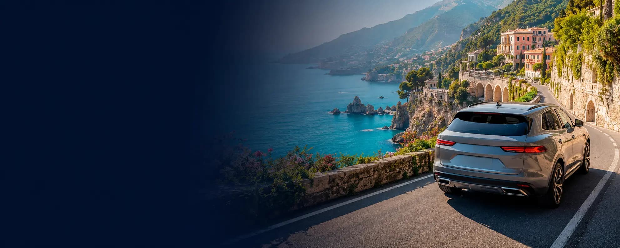 A premium SUV on a Mediterranean coastal road at sunset